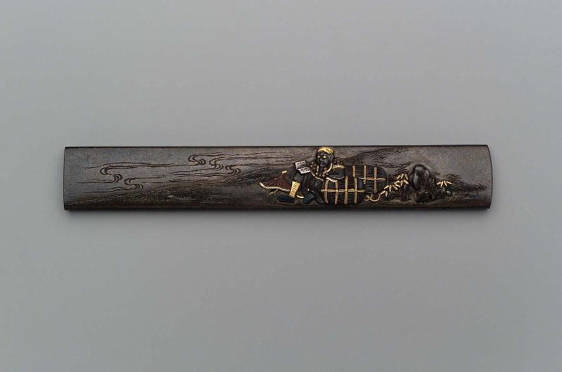 Kozuka with design of Daikoku reading a book, resting on two rice bales