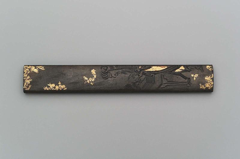 Kozuka with design of a Chinese official holding a feather fan standing by a desk with books