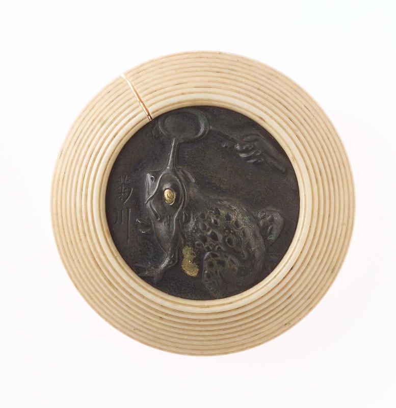 Kagami netsuke with design of a hand pouring water over a toad from a dipper